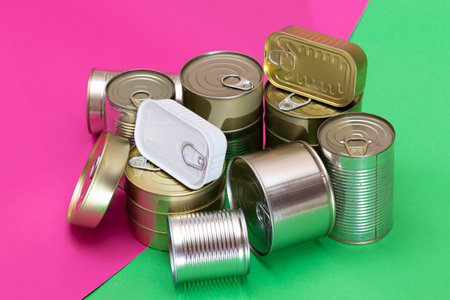 A Group of Stacked Tin Cans on Split Green and Cyan Background. Canned Food. Aluminum Cans for Safe and Long Term Storage of Food. Steel Sealed Food Storage Containersの写真素材