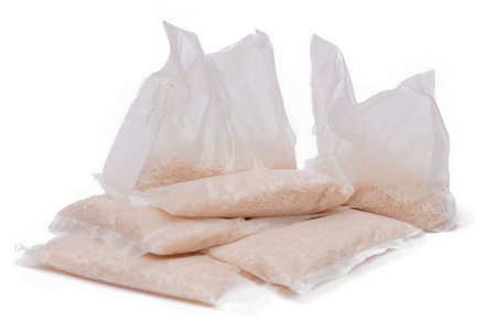 A Plastic Bags of White Long Grain Rice - Isolated on White Background. Small Transparent Packages with Dry Rice - Isolationの写真素材