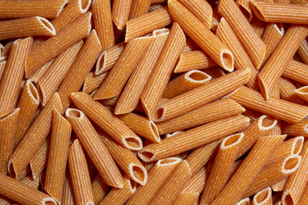 Uncooked Whole Grain Penne Rigate Pasta: A Culinary Canvas of Whole Wheat Macaroni, Creating a Lively and Textured Background for Gourmet Cooking. Whole Grain Dry Pasta. Whole Wheat Raw Macaroniの写真素材