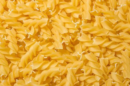 Uncooked Fusilli Pasta: A Culinary Canvas of Spiral Macaroni, Creating a Lively and Textured Background for Gourmet Cooking. Dry Pasta. Raw Macaroni - Top View, Flat Layの写真素材