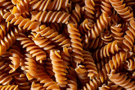 Uncooked Whole Grain Fusilli Pasta: A Culinary Canvas of Whole Wheat Spirals, Creating a Lively and Textured Background for Gourmet Cooking. Whole Grain Twisted Dry Pasta. Whole Wheat Raw Macaroniの写真素材