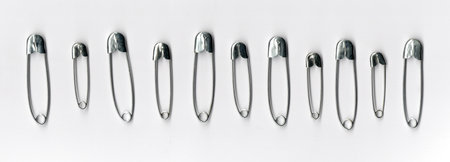 Many metal safety pins on white background, top view, flat lay