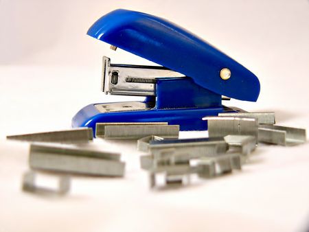 Blue stapler and staples on a white backdropの写真素材
