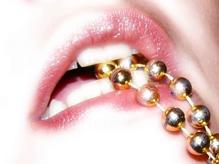Woman's mouth with beads held in her teethの写真素材