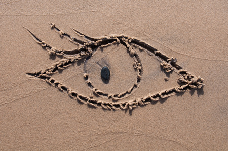 eye drawn in the sand. Beach background. Top viewの写真素材