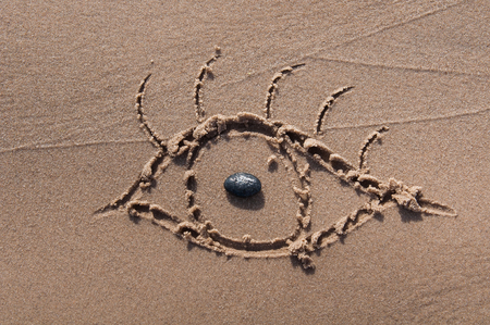 eye drawn in the sand. Beach background. Top viewの写真素材