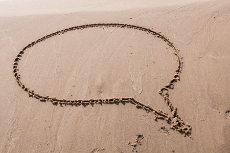 A speech or think bubble drawn out on a sandy beach. Beach background. Top viewの写真素材