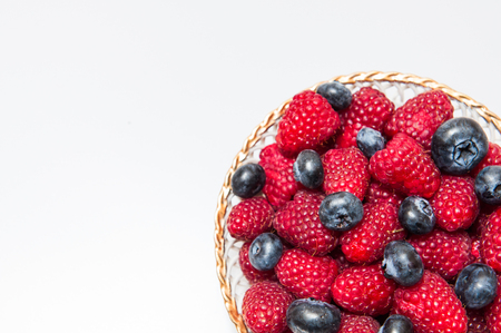 Fresh blueberry and raspberry on a white plate isolated on white backgroundの写真素材