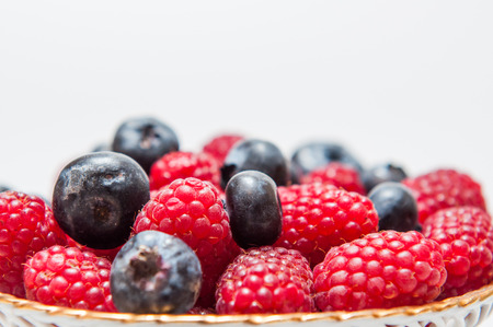 Fresh blueberry and raspberry on a white plate isolated on white background