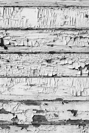 Wooden wall with cracked old white paint. Weathered painted white wooden plank, grunge vertical background or texture.の写真素材