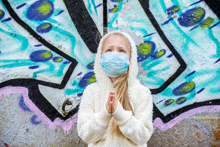 Child girl wearing respirator mask asks for help