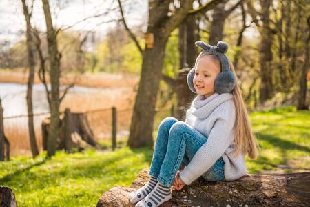 Little girl sits on a big stump in nature in springの写真素材