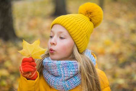 Little girl with blond hair in autumn backgroundの写真素材