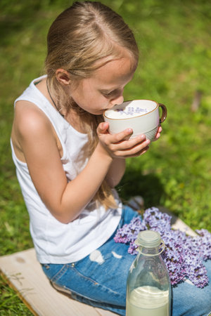 Little girl with cup of milk on natureの写真素材