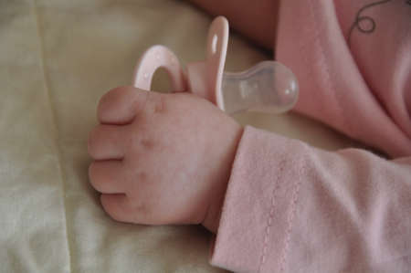 Baby hand with a nipple. Close up of baby hands with pacifier. Focus is on hands.