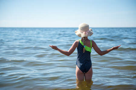Cute little blond girl swimming in the sea back viewの写真素材