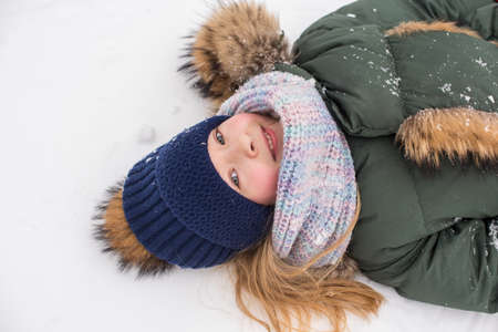 Happy child girl plaing with snow on a snowy winter walkの写真素材
