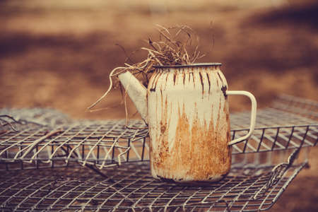 Old kettle stands on metal grid. A teapotの写真素材