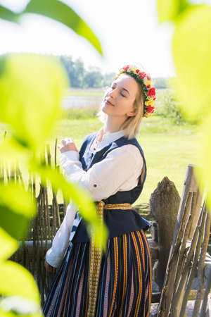 Latvian woman in traditional clothing posing on nature in village.の写真素材