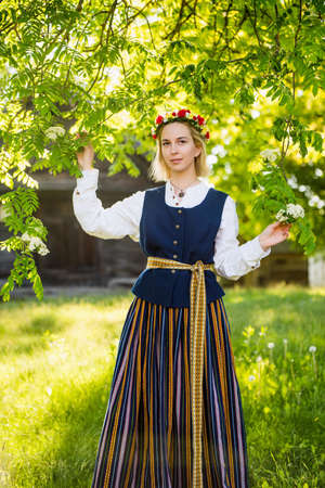 Latvian woman in traditional clothing posing on nature in village.の写真素材