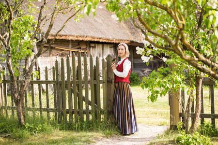 Woman in traditional clothing posing on nature in village.の写真素材