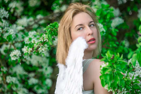 Beautiful feminime woman with white wings with white spring flowers.の写真素材