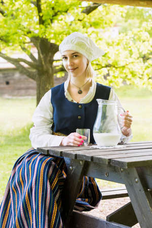Woman in traditional clothing with milk glass on natureの写真素材