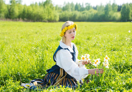 Young woman in national dress in a field with daffodils flowersの写真素材
