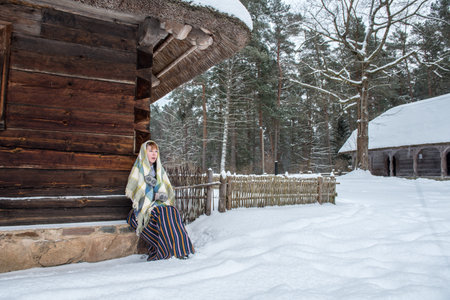 Latvian woman in traditional ethnic clothing posing on nature winter background in village.の写真素材