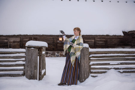 Latvian woman in traditional ethnic clothing posing on nature winter background in village. Riga Latviaの写真素材