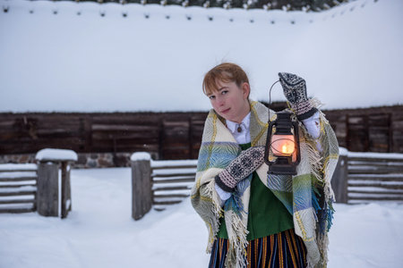 Latvian woman in traditional ethnic clothing posing on nature winter background in village.の写真素材