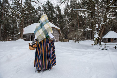 Latvian woman in traditional ethnic clothing posing on nature winter background in village.の写真素材