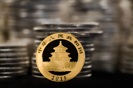 This Chinese Gold Coin has piles of Silver Coins in the background.の写真素材