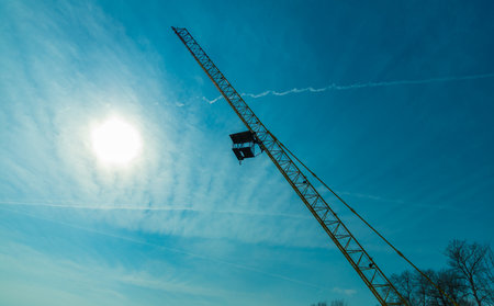 Silhouette of a construction crane on a background of blue skyの写真素材