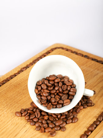 Coffee beans in a white cup on a wooden board.