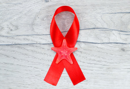 Red ribbon with starfish on wooden background. World AIDS day conceptの写真素材
