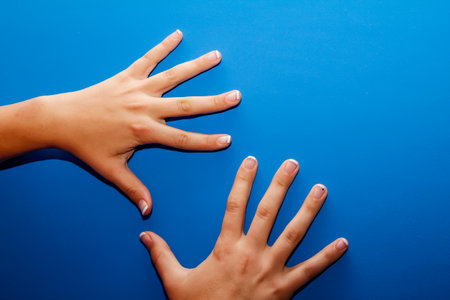 Hands of a girl on a blue background. View from above.