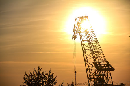 Silhouette of a construction crane on a background of the setting sun