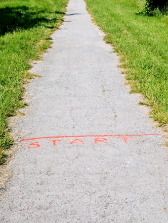 Spray-painted orange start line on straight gravel path between grass 