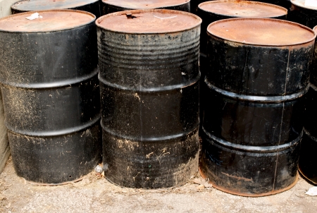 Row of rusting old black metal barrels 
