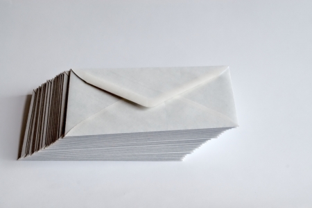 Stack of white envelopes shifted to right on white background の写真素材