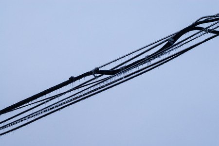 Several black cables covered in ice across empty gray background.の写真素材