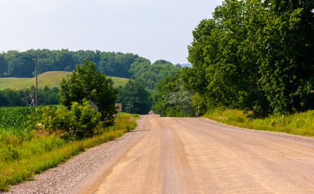 Rural country dirt road against distant hills and trees.の写真素材