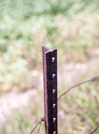 Single old rusted T-shaped vertical metal bar and wire against blurred background.の写真素材