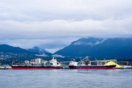 VANCOUVER, CANADA - OCTOBER 30, 2018:  Two cargo ships are docked in Vancouver Harbour, in front of...