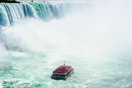 NIAGARA FALLS, CANADA - AUGUST 27, 2017: A tour boat full of passengers in red raincoats gets close to the Horseshoe Falls.のeditorial素材