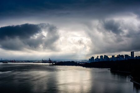Sun breaking through dark clouds in dramatic high contrast over Vancouver, British Columbia, Canada.