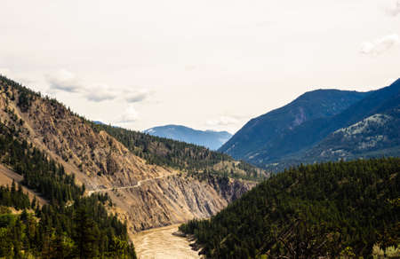 Mountains and road under overcast sky along Fraser River, British Columbia, Canada.の写真素材