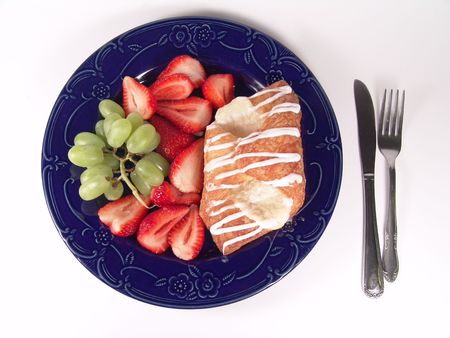 Pastry, grapes and strawberry on a blue plate with utensilの写真素材
