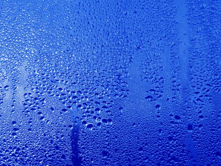 Close-up clear drops of water on window glass surface                               の写真素材